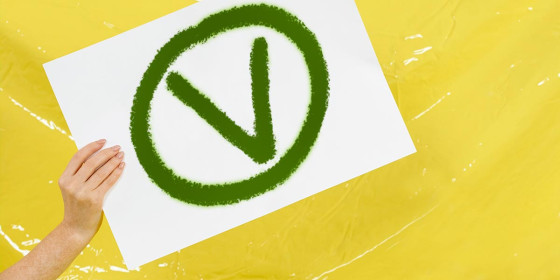 Eine Hand hält ein Plakat mit einem grünen „V“